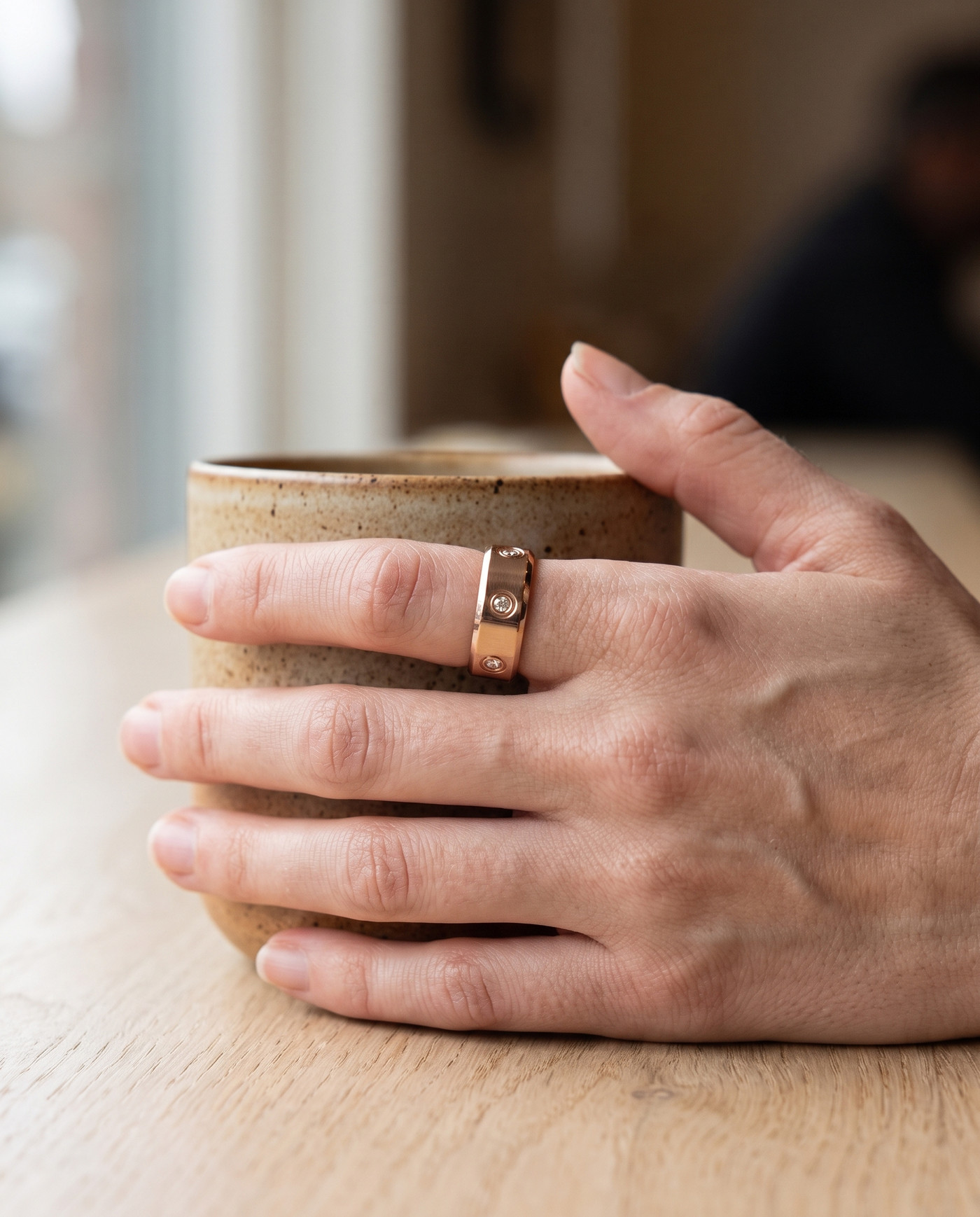 The LuxenX ring worn on the index finger, hand around a coffee cup